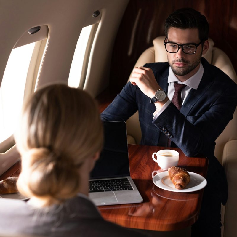 corporate businesspeople working with laptop in airplane