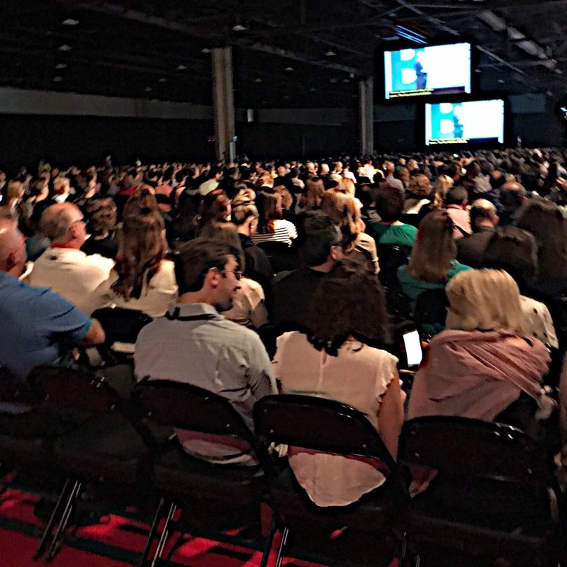 Large Audience crowd gathering at a conference watching the guest speaker on the main stage